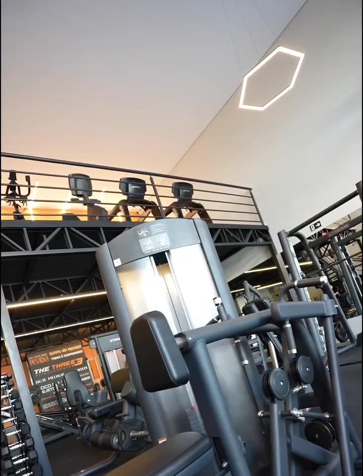 Salão de musculação com mezanino e luminárias hexagonais