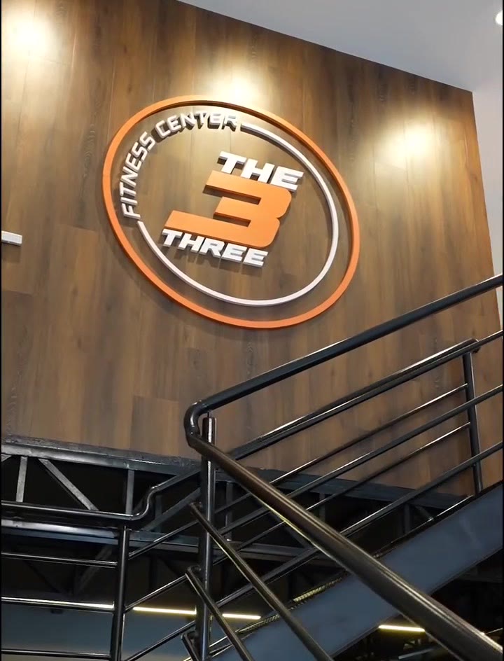 Parede de madeira com o selo The Three e escada de metal