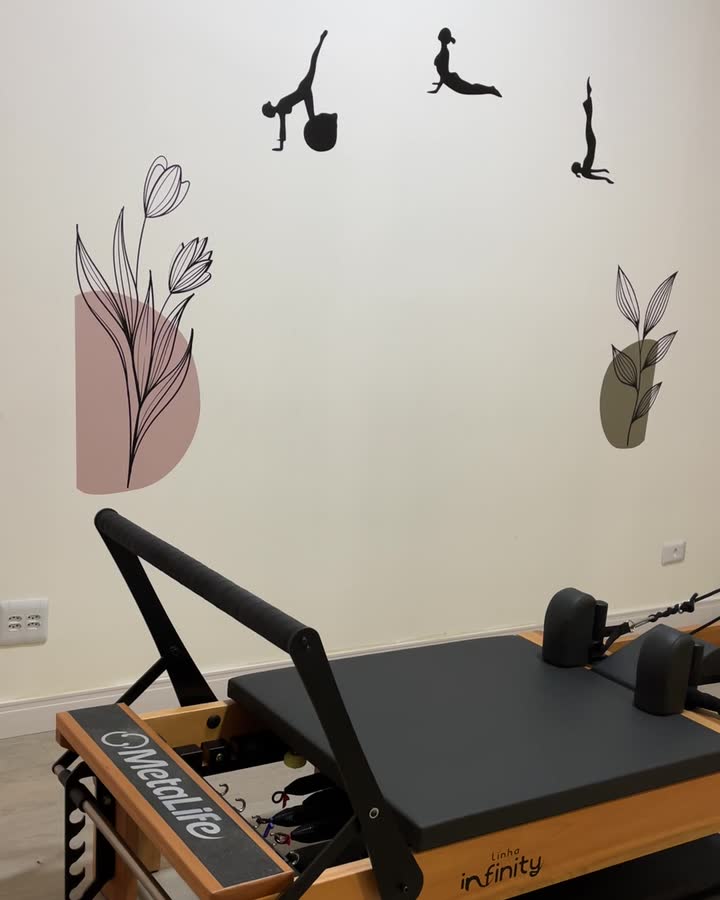 Aparelho reformer na sala de pilates, com figuras desenhadas na parede